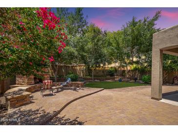 Paver-covered backyard features a built-in fireplace, seating, and a lush green lawn at 5208 W Straight Arrow Ln, Phoenix, AZ 85083