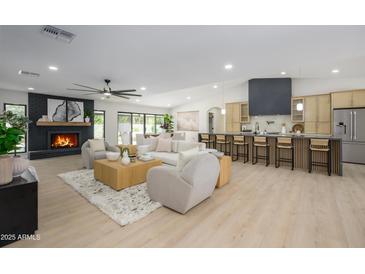 Bright open-plan living space featuring a fireplace, kitchen with bar seating, and neutral-toned decor at 5937 E Corrine Dr, Scottsdale, AZ 85254
