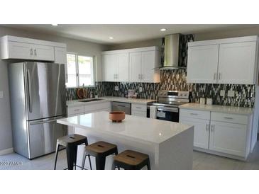 Modern kitchen featuring white cabinets, stainless steel appliances, quartz countertops and decorative backsplash at 8750 E Starlight Way, Scottsdale, AZ 85250