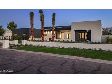 Modern home exterior with a manicured lawn, palm trees and a sleek design at 6303 E Via Estrella Ave, Paradise Valley, AZ 85253