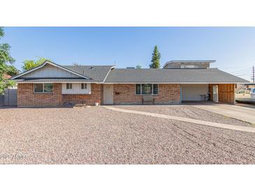 Charming single-story brick home featuring a low-maintenance gravel yard and covered carport at 1235 E Dover St, Mesa, AZ 85203