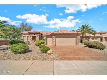 Charming home featuring a three-car garage, desert landscaping, and a red tile roof at 15101 W Waterford Dr, Surprise, AZ 85374