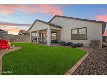 Inviting backyard with lush artificial grass, a covered patio, and cozy lounging area with a fire pit at 17140 W Running Deer Trl, Surprise, AZ 85387
