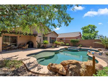 Backyard oasis with a freeform pool, rock features, and lush landscaping provides a relaxing outdoor space at 24886 W Huntington Dr, Buckeye, AZ 85326