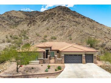 Charming home with a tile roof and stone accents, nestled against a scenic desert mountain backdrop at 2722 W Hiddenview Dr, Phoenix, AZ 85045