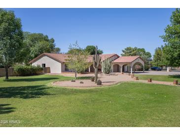 Charming single-story home featuring a landscaped front yard with mature trees and desert landscaping at 3357 N Ashbrook E St, Mesa, AZ 85213
