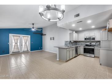 Bright living room adjacent to kitchen features neutral colors, ceiling fan, and access to backyard patio at 3178 W Williams Dr, Phoenix, AZ 85027
