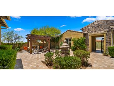 Inviting backyard patio featuring a fireplace, pergola, water feature, and desert landscaping at 36813 N 109Th Way, Scottsdale, AZ 85262