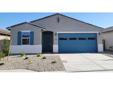 Charming single-story home featuring a blue garage door and a well-maintained, low maintenance front yard at 37198 W Vera Cruz Dr, Maricopa, AZ 85138