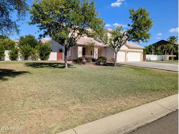 Charming two-story home with a well-maintained front yard and mature trees under a clear blue sky at 1015 S 132Nd St, Gilbert, AZ 85233