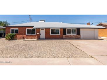 Charming brick home featuring a gravel front yard, white trim, and a single-car garage at 1028 W 5Th St, Mesa, AZ 85201