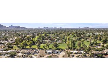 Expansive aerial view of a luxurious home, a golf course, and the desert landscape with mountains in the background at 10804 N 60Th Pl, Scottsdale, AZ 85254