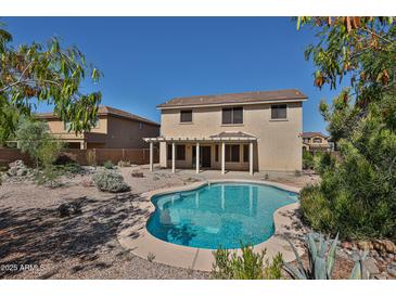 Backyard view of sparkling in-ground pool, rock landscaping, and covered patio, perfect for outdoor entertaining at 1114 S 220Th Ave, Buckeye, AZ 85326