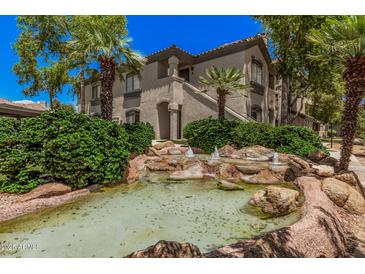 Attractive building with landscaped water feature, mature trees, and charming architectural details at 15095 N Thompson Peak Pkwy # 1005, Scottsdale, AZ 85260