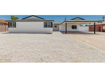 Exterior view of a bright white home features rock landscaping, fresh paint and trim, and a covered carport at 4613 N 53Rd Dr, Phoenix, AZ 85031