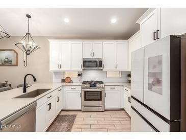 Modern kitchen features white cabinetry, stainless steel appliances, and a stylish faucet at 9624 E Thunderbolt Ave, Mesa, AZ 85212