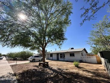 Charming single-story home featuring white painted brick and low maintenance front yard with large shade tree at 1214 E Henry St, Tempe, AZ 85288