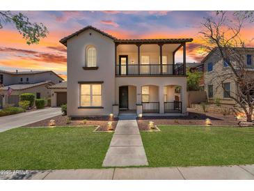 Charming two-story home showcasing stucco finish, landscaped lawn, covered balcony, and inviting curb appeal at sunset at 20507 W Daniel Pl, Buckeye, AZ 85396