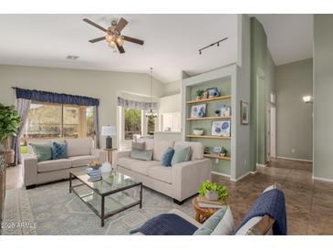 Bright living room featuring neutral furniture, a ceiling fan, and charming built-in shelving at 3055 N Red Mtn # 77, Mesa, AZ 85207