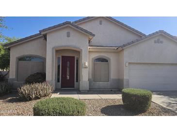 Charming single-story home featuring a well-manicured yard, neutral tones, and a lovely red front door at 43634 W Roth Rd, Maricopa, AZ 85138