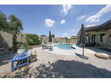 Inviting backyard pool with lounge chairs, umbrellas, and desert landscaping on a sunny day at 5416 W Village Dr, Glendale, AZ 85308