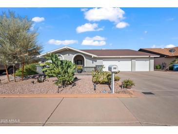 Charming single-story home featuring desert landscaping, a three-car garage, and an inviting arched entryway at 6715 S Lakeshore Dr, Tempe, AZ 85283