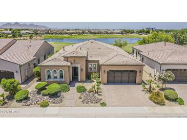 Stunning single-story home with lush landscaping, neutral tones, three-car garage, and a beautiful view of the golf course and lake at 36172 N Secret Garden Path, Queen Creek, AZ 85140