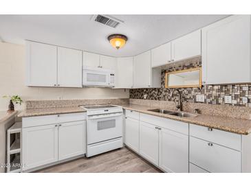 Bright kitchen features white cabinetry, granite countertops, and stainless-steel appliances at 8210 E Garfield St # K23, Scottsdale, AZ 85257