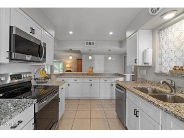 Modern kitchen with stainless steel appliances, granite countertops, and ample storage at 10895 W Clair Dr, Sun City, AZ 85351