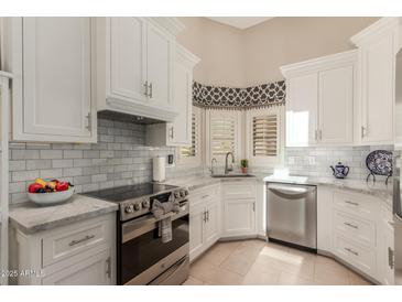 Updated kitchen featuring marble backsplash, white cabinets, and stainless steel appliances at 13041 S 45Th Pl, Phoenix, AZ 85044