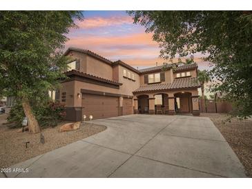 Gorgeous two-story home with a three-car garage, lush landscaping, and a warm, inviting facade at sunset at 14517 W Cortez St, Surprise, AZ 85379