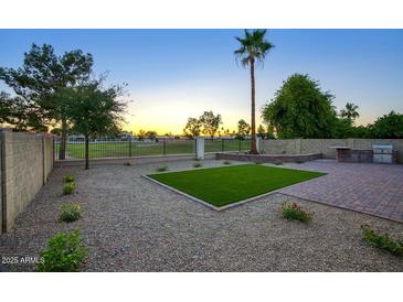 A landscaped backyard with artificial turf, a built-in grill, and views of the surrounding golf course at 19906 N 76Th Ave, Glendale, AZ 85308