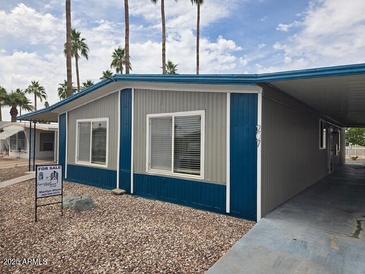 Charming manufactured home with a covered carport and desert landscaping in a well-maintained community at 3104 E Broadway Rd # 207, Mesa, AZ 85204