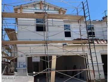 Exterior of home under construction featuring white facade, windows, two-car garage, and temporary scaffolding at 5851 E Covey Ln, Phoenix, AZ 85054