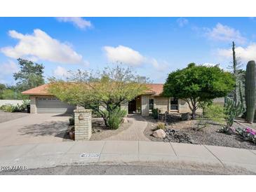 Charming single-story brick home featuring mature desert landscaping, a tile roof, and an attached two-car garage at 13019 N 23Rd Pl, Phoenix, AZ 85022