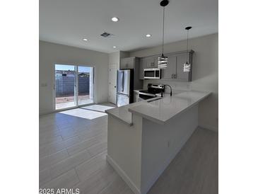 Bright kitchen featuring stainless steel appliances, gray cabinets, and a quartz countertop island at 14860 S Capistrano Rd, Arizona City, AZ 85123