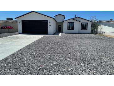 Beautifully renovated single-story home with a modern exterior, new garage door, and low-maintenance gravel yard at 1835 E Burgess Ln, Phoenix, AZ 85042