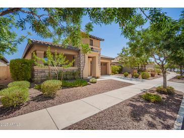 Desirable single-Gathering home featuring a two-car garage, stone accents, and mature desert landscaping at 20499 W Alsap Rd, Buckeye, AZ 85396