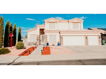 Beautiful two-story home showcasing a well-manicured lawn, lovely landscaping, and a charming red windmill at 2130 N Cypress Point N Way, Casa Grande, AZ 85122