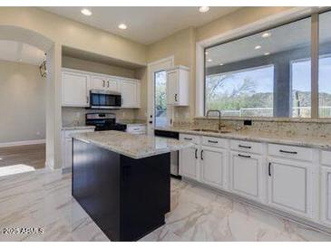 Bright kitchen with white cabinets, a black island, and marble floors, offering a stylish and functional space at 3634 N Desert Oasis --, Mesa, AZ 85207