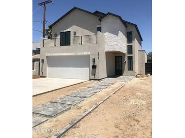 Modern two-story home featuring a white brick accent wall and a concrete driveway with decorative gray pavers at 3831 N 8Th St, Phoenix, AZ 85014
