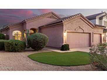 Inviting home exterior featuring a three car garage, desert landscaping, and a touch of artificial grass at 689 E Stottler Dr, Gilbert, AZ 85296