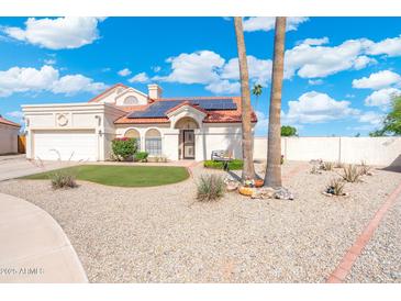 Charming single-story home with manicured desert landscaping, solar panels and a red tile roof at 7503 W Julie Dr, Glendale, AZ 85308