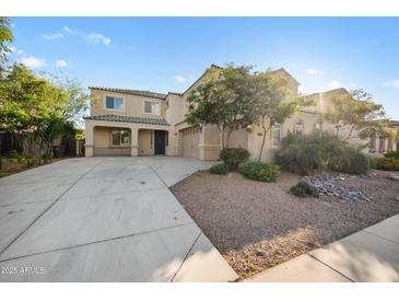 Two-story beige home featuring three-car garage and landscaped front yard under a bright blue sky at 22193 E Via Del Oro --, Queen Creek, AZ 85142