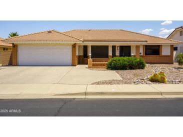 Single story home with a two car garage, desert landscaping, a terracotta roof and a well manicured lawn at 8230 E Navarro Ave, Mesa, AZ 85209