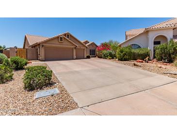 Charming home exterior featuring a wide driveway, three-car garage, and desert landscaping with lush flowering bushes at 10931 N 129Th Way, Scottsdale, AZ 85259