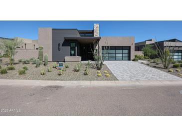 Contemporary home featuring desert landscaping, stone accents, and a modern glass-paned garage door at 37200 N Cave Creek Rd # 1045, Scottsdale, AZ 85262