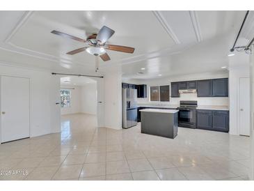 Bright kitchen features dark cabinetry, stainless steel appliances, and an island with stone countertops at 7551 W Pasadena Ave, Glendale, AZ 85303