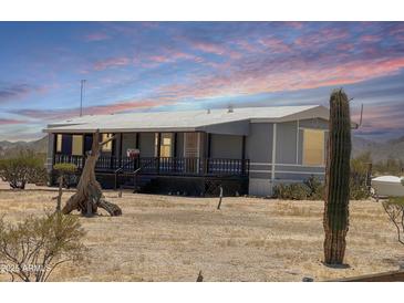 Single-story home featuring a covered porch and desert landscaping with beautiful desert sunsets at 50525 W Whirly Bird Rd, Maricopa, AZ 85139