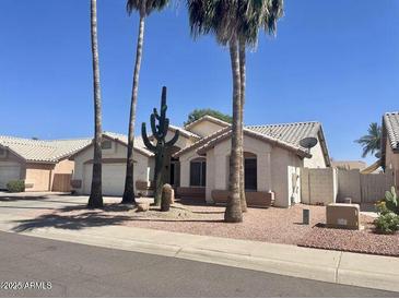 Charming single-story home with well-maintained landscaping, mature palm trees, and a desert-friendly yard at 8759 W Port Au Prince Ln, Peoria, AZ 85381